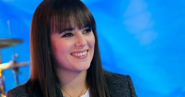 Alizée en portrait officiel, souriante et élégante en blazer sombre.