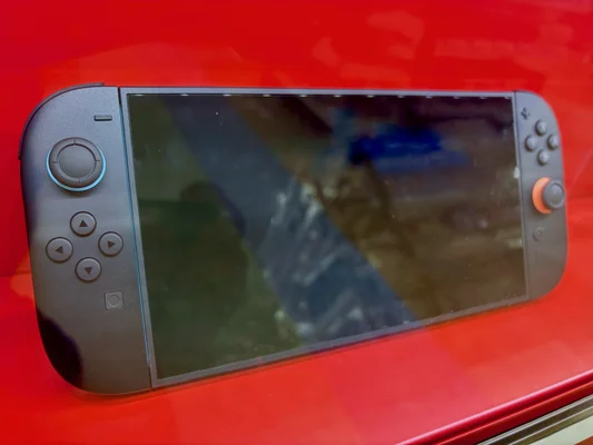 La Nintendo Switch 2 en mode portable posée sur un support rouge brillant.