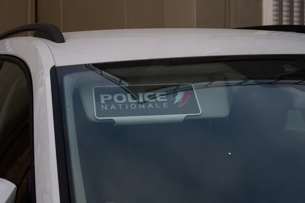 Un véhicule de la Police nationale stationné devant un bâtiment aux murs beiges.