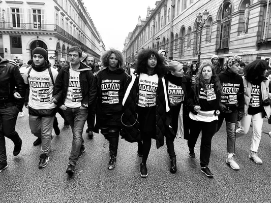 Militants du comité Adama marchant de manière coordonnée dans une rue.