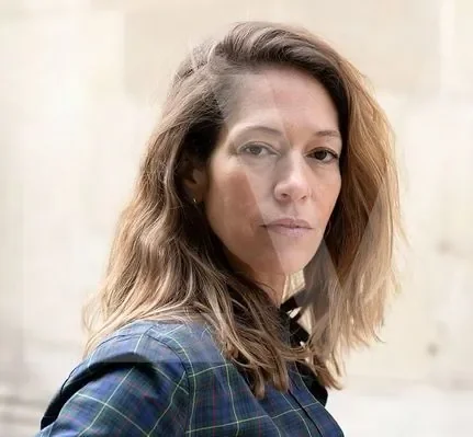 Aude Walker, autrice de Cavales, portant une veste bleue à carreaux sur fond neutre.