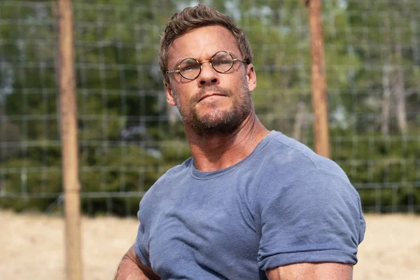 Alan Ritchson en plein air, affichant une silhouette athlétique.