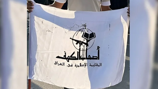 Une personne brandissant un drapeau blanc orné d'un emblème noir comprenant un globe, un livre et un fusil.