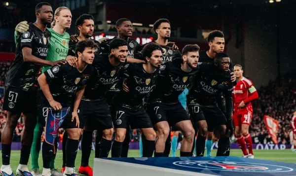 Joueurs de football en tenue noire et verte posant sur la pelouse.