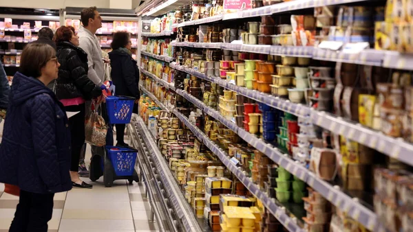 Des acheteurs choisissant des produits sur les rayons d'un supermarché.