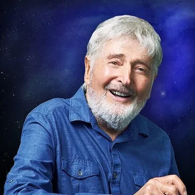 Le producteur Sid Krofft posant devant un fond d'étoiles bleues.