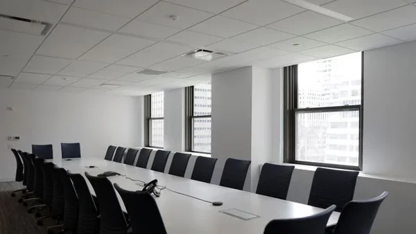 Une salle de réunion lumineuse au design minimaliste avec une grande table blanche et une vue sur la ville.