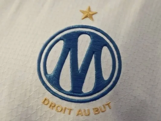 Le nouveau logo de l'OM brodé sur un tissu blanc.