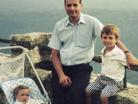 Des membres de la famille du juge Borrel debout sur un banc de pierre dans un paysage brumeux.