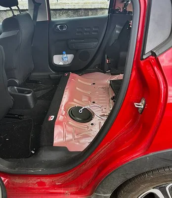 L'intérieur d'une Citroën C3 montrant le sol métallique exposé suite au vol de la banquette arrière.