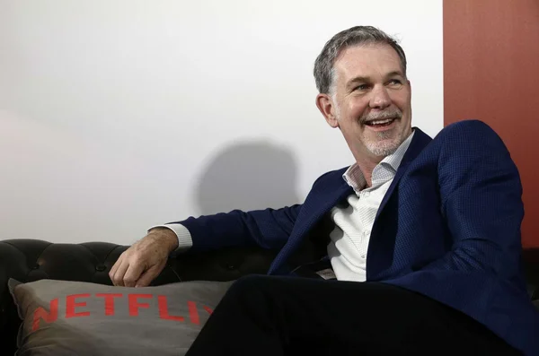 Reed Hastings posant avec un coussin aux couleurs de Netflix.