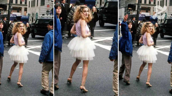 Une femme portant le tutu blanc culte et un haut rose dans une rue de ville.