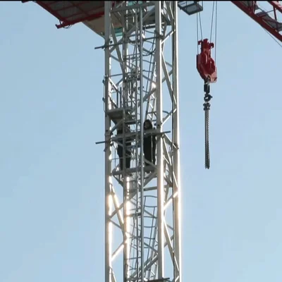 Vue en plongée d'une grue avec deux personnes sur la plateforme et le crochet de levage à Nice.