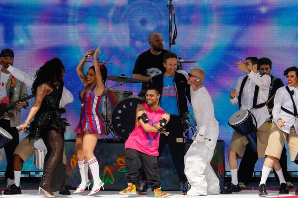 Le groupe Coldplay lors d'une performance pour la FIFA avec des danseurs et des costumes colorés.