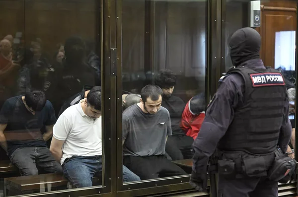 Les accusés de l'attaque du Crocus City Hall dans le box des détenus au tribunal, encadrés par les forces de l'ordre russes