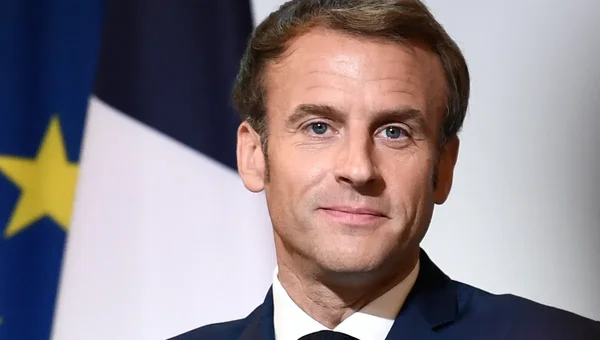 Portrait d'Emmanuel Macron, le plus jeune président de l'histoire de France, devant les drapeaux officiels.