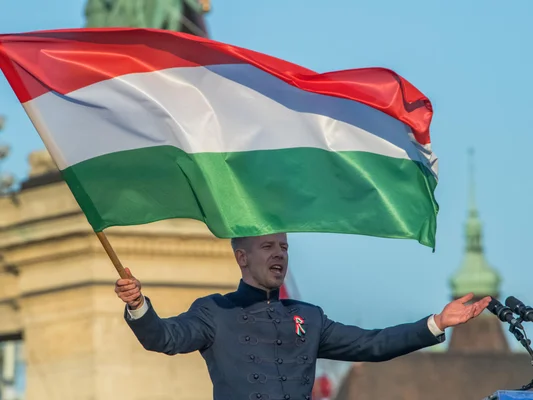 Péter Magyar brandissant fièrement le drapeau national hongrois lors d'un rassemblement.