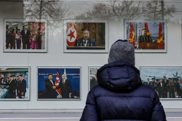 Visiteur observant une exposition de photographies officielles liées à l'engagement militaire nord-coréen.