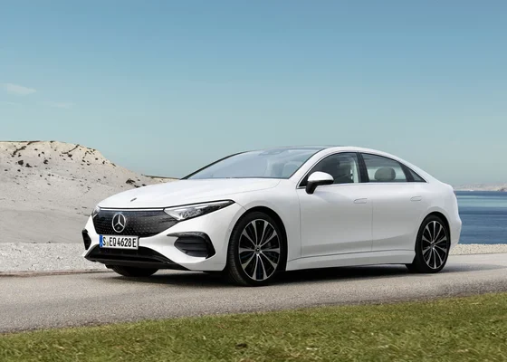 Une Mercedes-Benz EQS électrique blanche dans un paysage côtier.