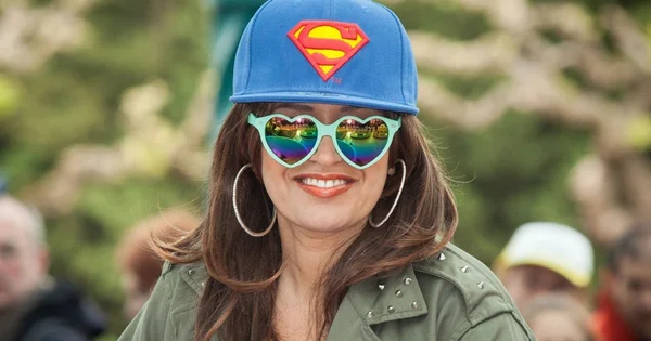 Laââm affichant un style coloré avec une casquette Superman et des lunettes de cœur.