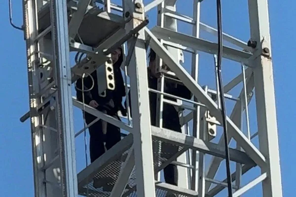 Deux femmes retranchées dans la charpente d'une grue sur un chantier à Nice sous un ciel dégagé.