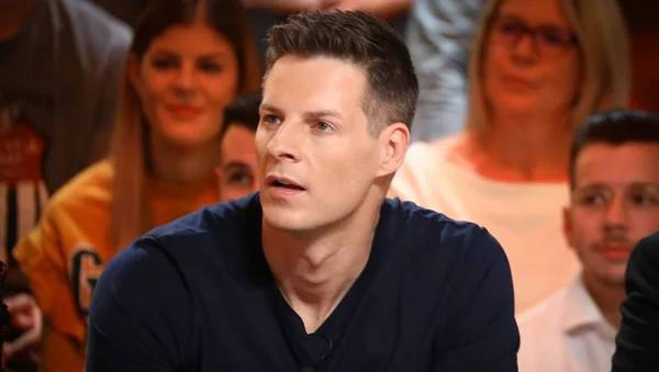 Matthieu Delormeau entouré de personnes dans un cadre public.