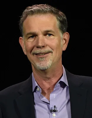 Reed Hastings, cofondateur de Netflix, portant une chemise violette et un blazer sombre.