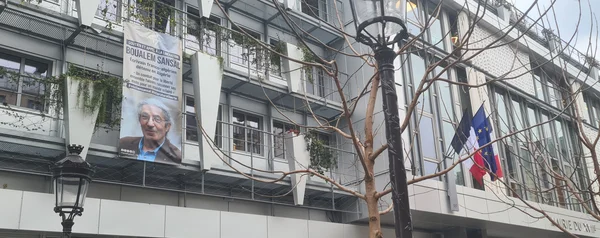 Bannière demandant la libération de Boualem Sansal accrochée sur une façade aux Batignolles, avec des drapeaux français et européen