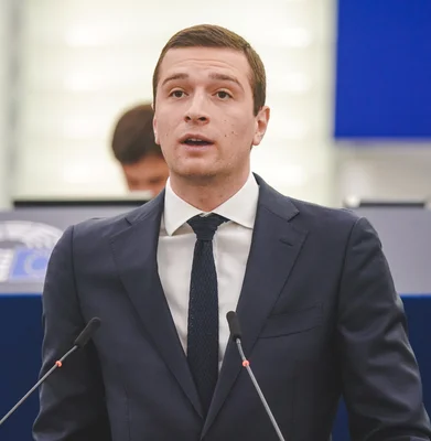 Jordan Bardella s'exprimant depuis une tribune avec des microphones au Parlement européen.