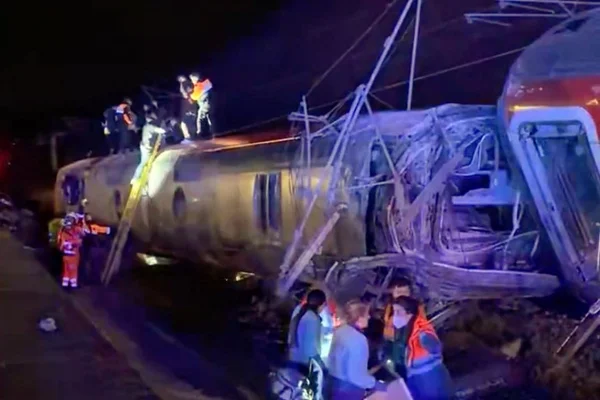 Un train déraillé aux portes taguées est inspecté près d'un tunnel en Espagne.
