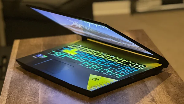 Le MSI Crosshair 15 posé sur du marbre avec son écran affichant un paysage côtier et une plante en pot à côté.