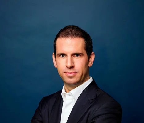 Portrait de l'ancien conseiller ministériel, connu pour ses positions sur les OVNI, en costume sombre sur fond bleu.