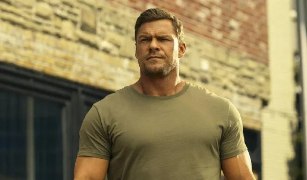 Alan Ritchson en blazer sombre et chemise blanche lors d'une apparition publique.