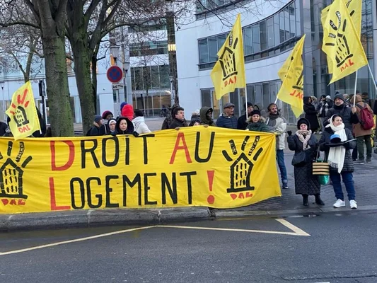 Des manifestants défilant avec une bannière réclamant le droit au logement.