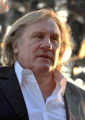 Portrait de Gérard Depardieu en chemise blanche et veste sombre.