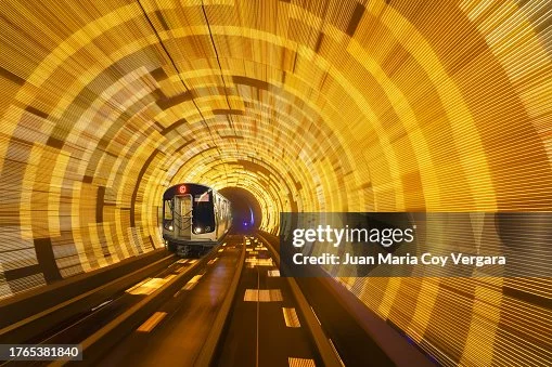 Train du métro filant dans un tunnel lumineux aux reflets dorés.