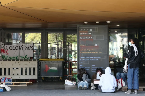 Manifestation devant l'Université de Strasbourg avec une banderole 'DÉCOLONISONS NOS UNIVERSITÉS'.