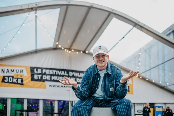 Un artiste posant devant les installations du festival Namur is a Joke.
