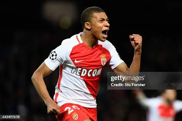 Un joueur de l'AS Monaco en action, célébrant une victoire sur le terrain avec son maillot rouge et blanc.
