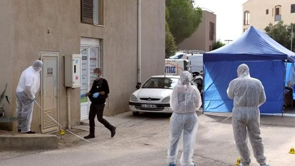 Enquêteurs en combinaison blanche sur une scène de crime avec une tente bleue.