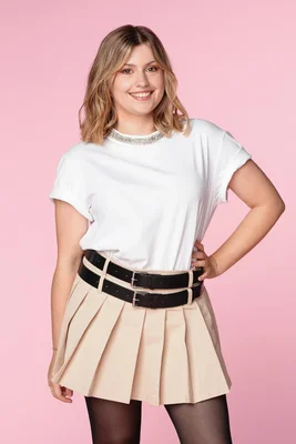 Marine Delplace posant dans une tenue composée d'un t-shirt blanc et d'une jupe beige.