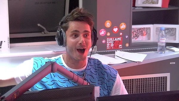 Guillaume Pley en studio avec son casque et l'affiche 'GUILLAUME RADIO 2.0'.
