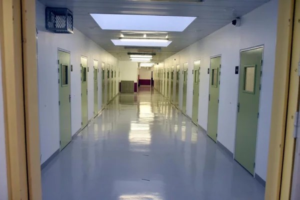 Vue d'un couloir intérieur aux murs blancs et portes vertes.