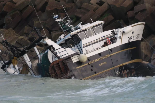 Le chalutier Le Chant Duloup, de Dieppe, s'enfonce dans l'eau turbulente près de la digue.