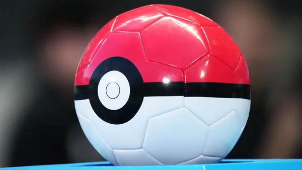 Un ballon de football aux couleurs d'une Poké Ball, symbole du lien entre sport et capture de monstres.