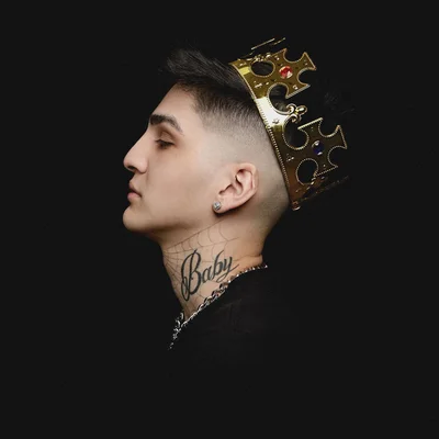 Abi, vu de profil, avec une couronne dorée et un tatouage 'Baby' sur le cou.