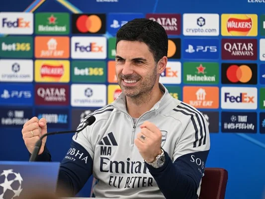 Pep Guardiola en conférence de presse, souriant et les poings serrés.