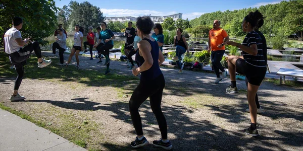 Des participants à une séance de sport gratuite organisée par la mairie de Bordeaux, s'entraînant en plein air près d'un étang.