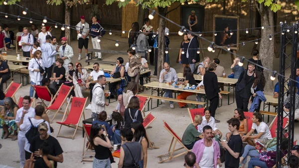 Ambiance du Festival Paris l'été : un public profite d'un espace extérieur convivial avec guirlandes et transats rouges.