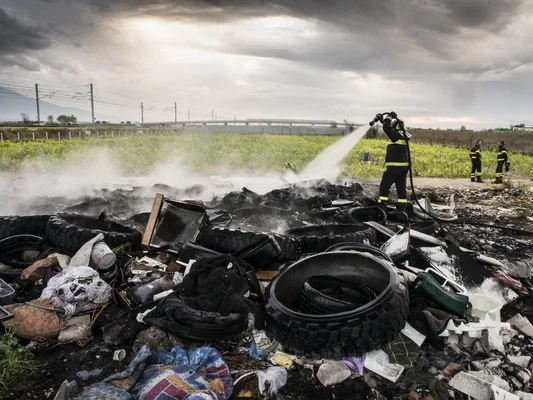 Pompier éteignant un incendie de déchets toxiques dans la « Terre des feux ».